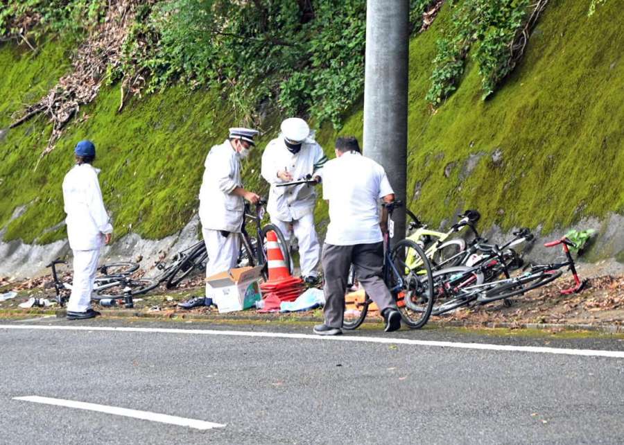 転倒したとみられる自転車などを道路脇で調べる警察官＝９月４日午前１１時４５分、南大隅町根占