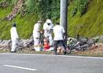 転倒したとみられる自転車などを道路脇で調べる警察官＝９月４日午前１１時４５分、南大隅町根占