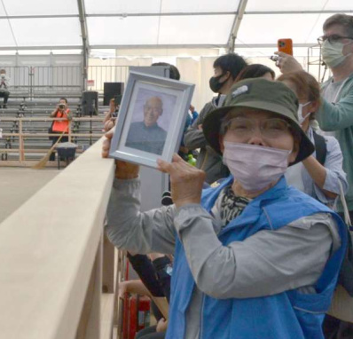 故小浜進さんの遺影を持って会場に駆けつけた妻のヨリ子さん＝８日、霧島市牧園
