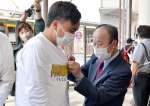 署名した人にブルーリボンを着ける市川健一さん＝１０日、鹿児島市