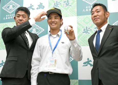 帽子をかぶりポーズをとる大野稼頭央投手（中央）と球団スカウト＝２５日、大島高校