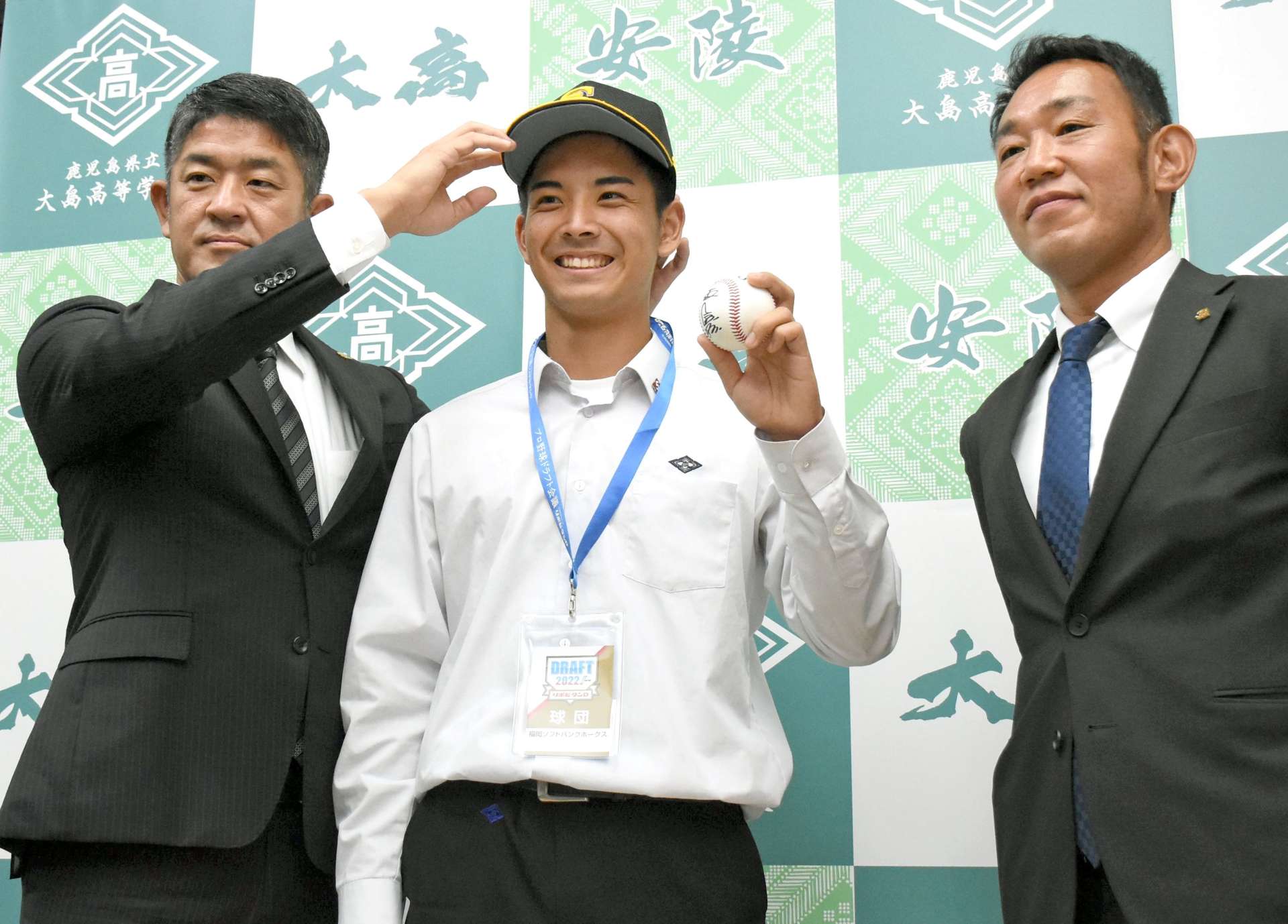 帽子をかぶりポーズをとる大野稼頭央投手（中央）と球団スカウト＝２５日、大島高校