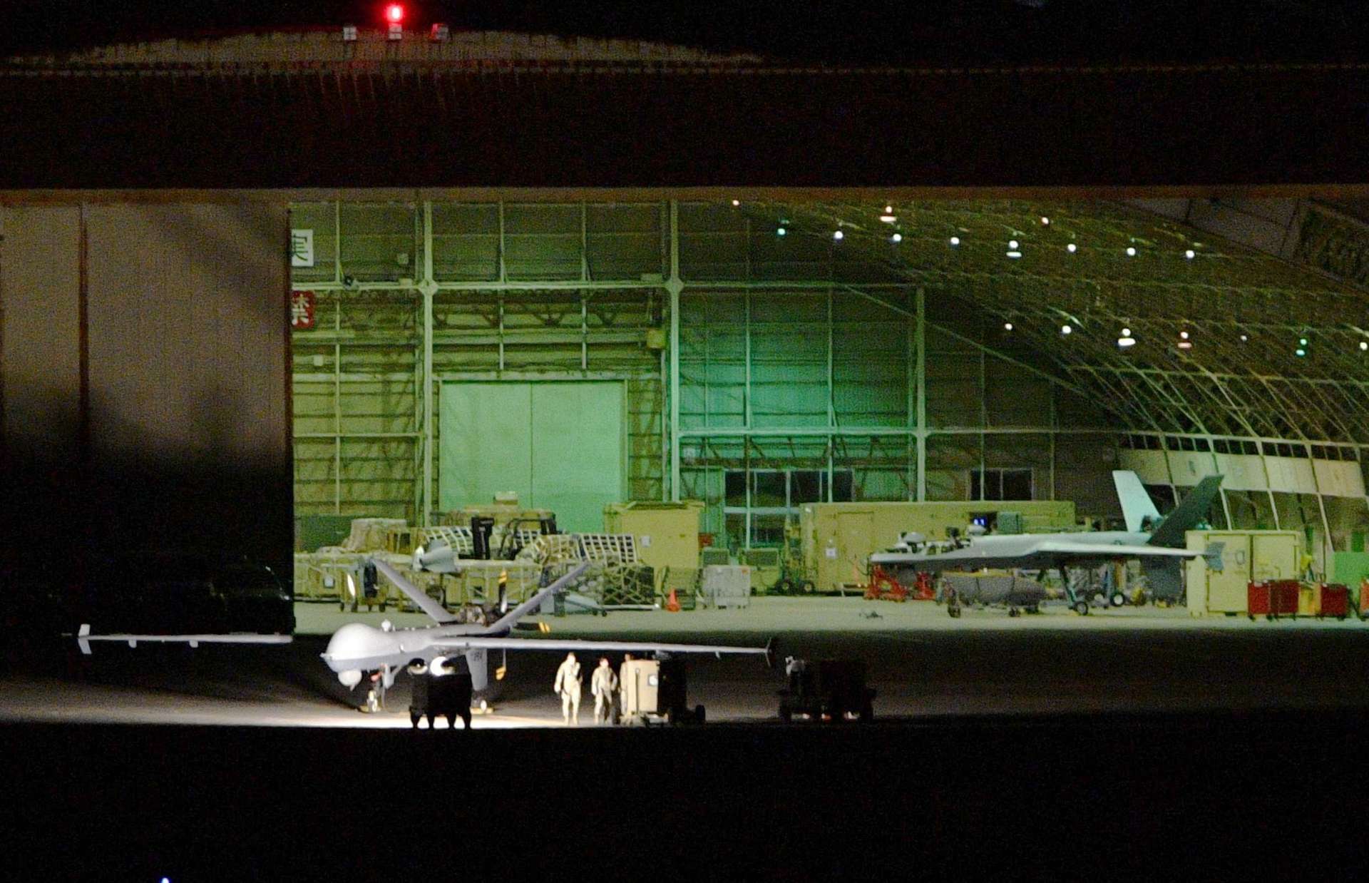 日没後も無人偵察機ＭＱ９（左手前）の整備など続ける米軍関係者。右奥にもう１機見える＝２７日午後６時４０分、鹿屋市野里町