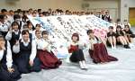 １１８番通報を啓発する作品の前で記念写真に収まるＩＭＡＬＵさん（中央）＝奄美市名瀬の大島高校
