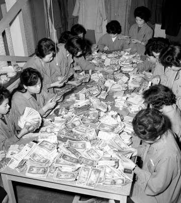 １日の売り上げを数えるデパートの従業員＝１９６１（昭和３６）年１２月１８日、鹿児島市金生町の山形屋