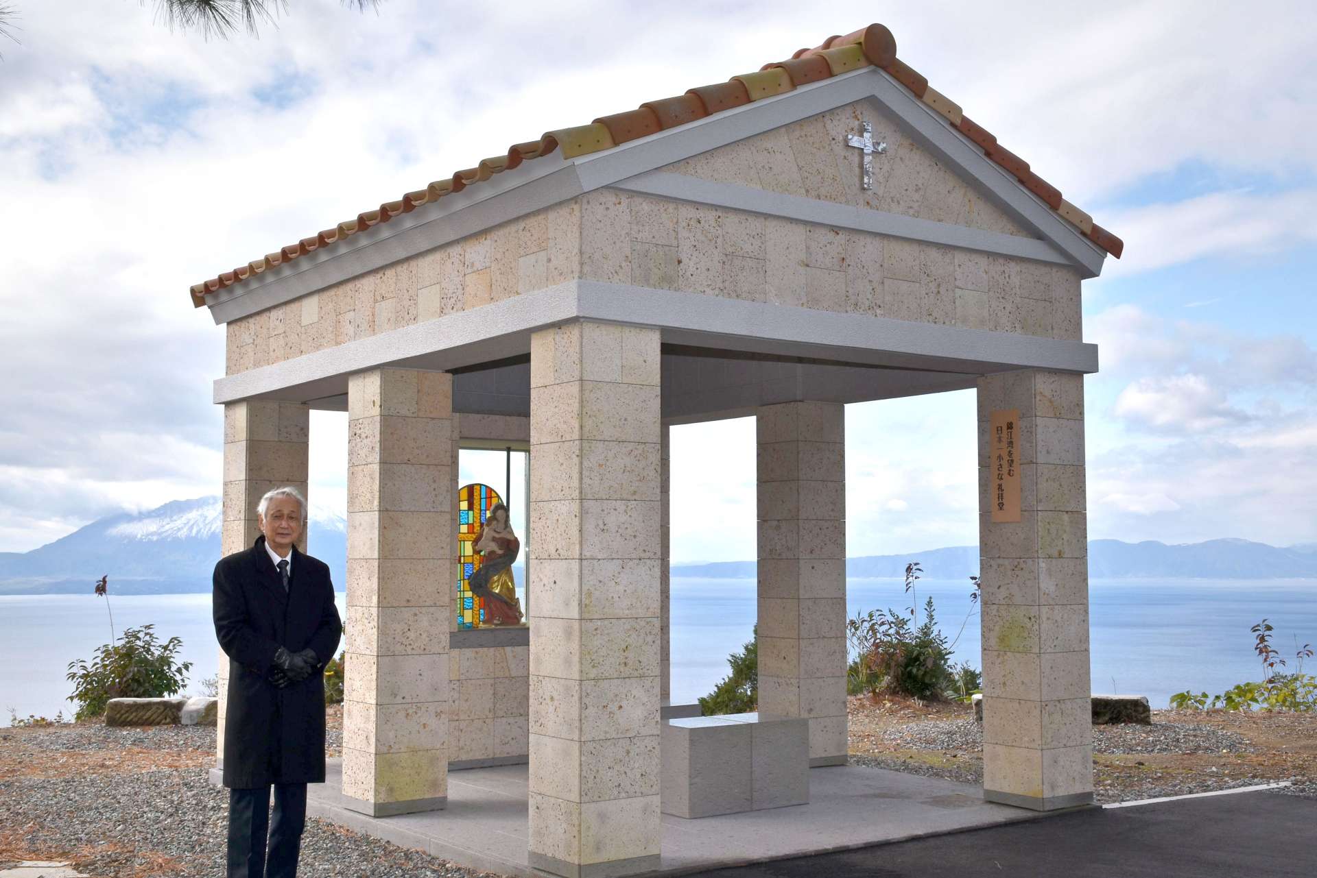 桜島と鹿児島湾を望む礼拝堂と松下兼介館長＝霧島市福山の寒山公園