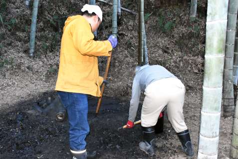 岩沢伝朗さん（左）の指導でポーラス竹炭づくりを研修する参加者＝薩摩川内市祁答院町黒木