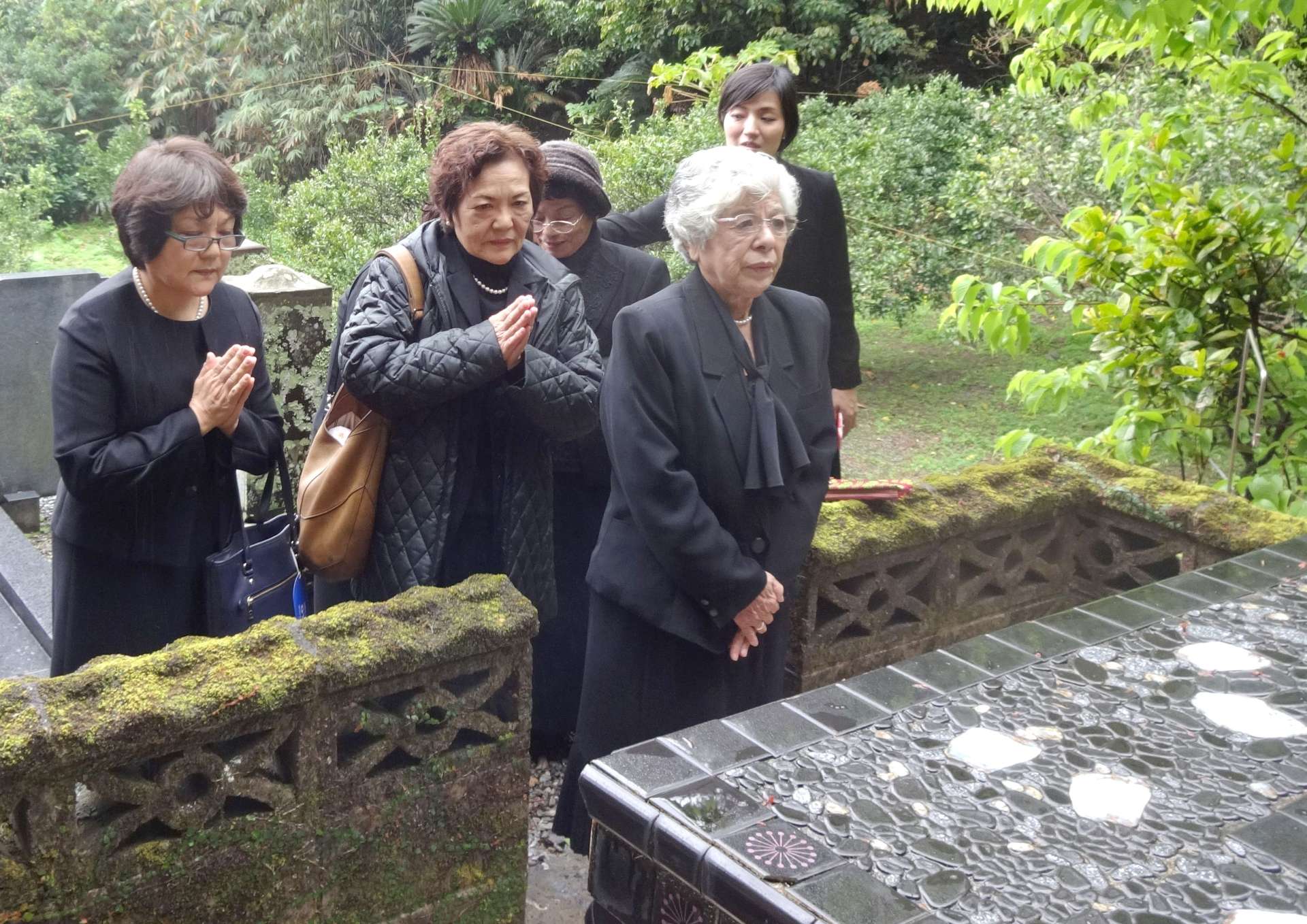 医師の碇元章世さんの墓参りをする平良啓子さん（手前）＝２０１７年３月、宇検村宇検（同村役場提供）