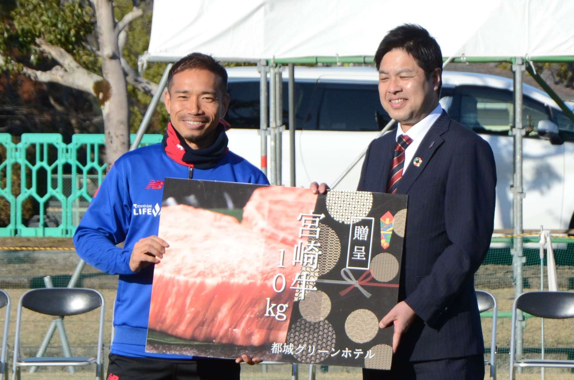 宮崎牛のパネルを受け取る長友佑都選手（左）＝１月３１日、都城市の高城運動公園