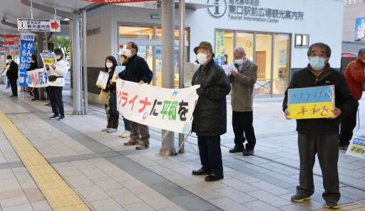 横断幕やプラカードを手に戦争終結を訴える人たち＝２４日、鹿児島市中央町のＪＲ鹿児島中央駅前