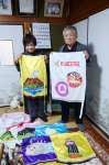 「稲盛会」で披露する相撲踊りのため手作りした化粧まわしを持つ稲盛勝也さん、たづ子さん夫妻＝鹿児島市小山田町