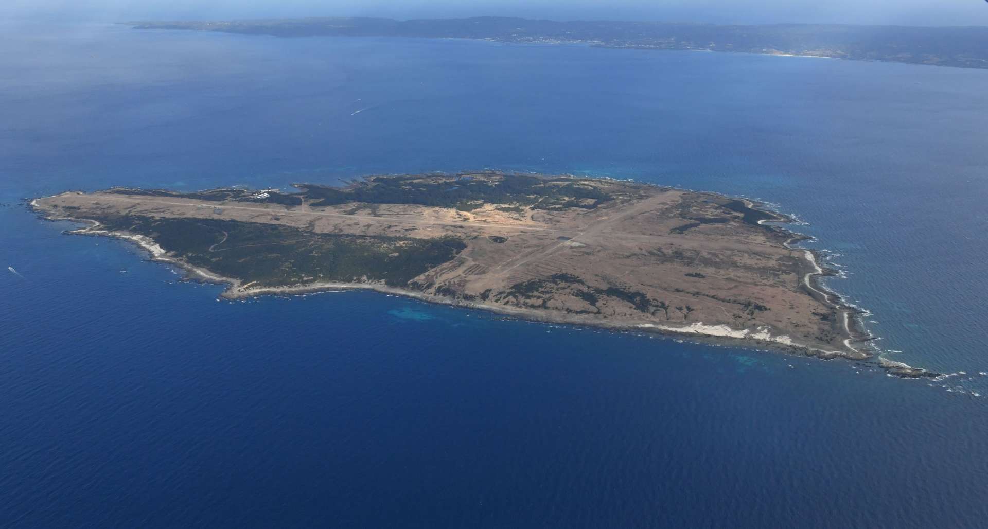 １月に自衛隊基地の本体工事が始まった西之表市馬毛島。奥は種子島＝１月１２日（本社チャーター機から）