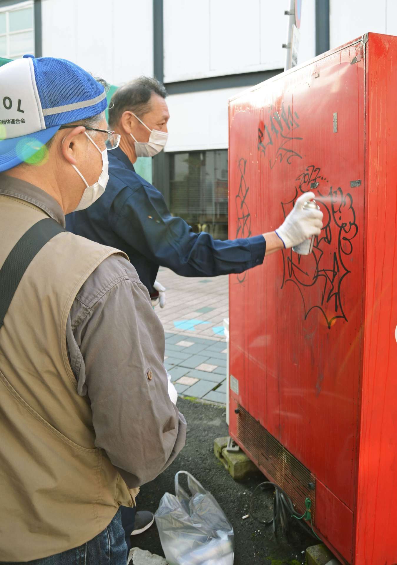 自販機裏の落書きを消す鹿児島中央警察署員ら＝１６日午前７時ごろ、鹿児島市の天文館地区