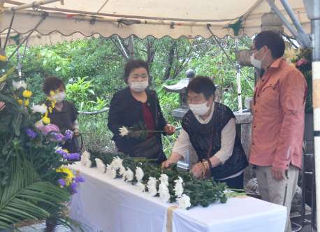 犠牲者を悼み、菊の花を供える遺族＝２０日、瀬戸内町古仁屋の森山公園