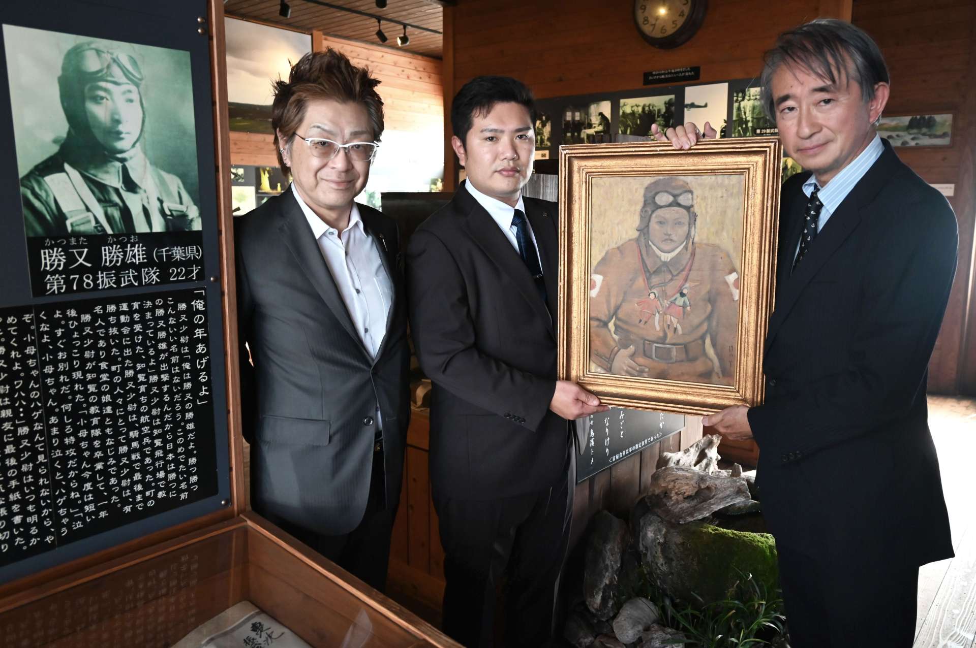 調所一郎さん（右）から肖像画を受け取るホタル館の鳥浜拳大館長（中央）とトメさんの孫赤羽潤さん＝２日、南九州市知覧