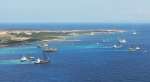 砂利などの投入で海中に帯のような筋が伸びる島の南東部＝１０日午前（小型無人機で撮影）