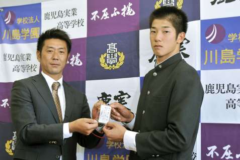 2013年10月、阪神の田中秀太九州担当スカウト（左）から和田豊監督直筆のメッセージを受け取る鹿児島実高の横田慎太郎選手＝鹿児島市の鹿児島実高