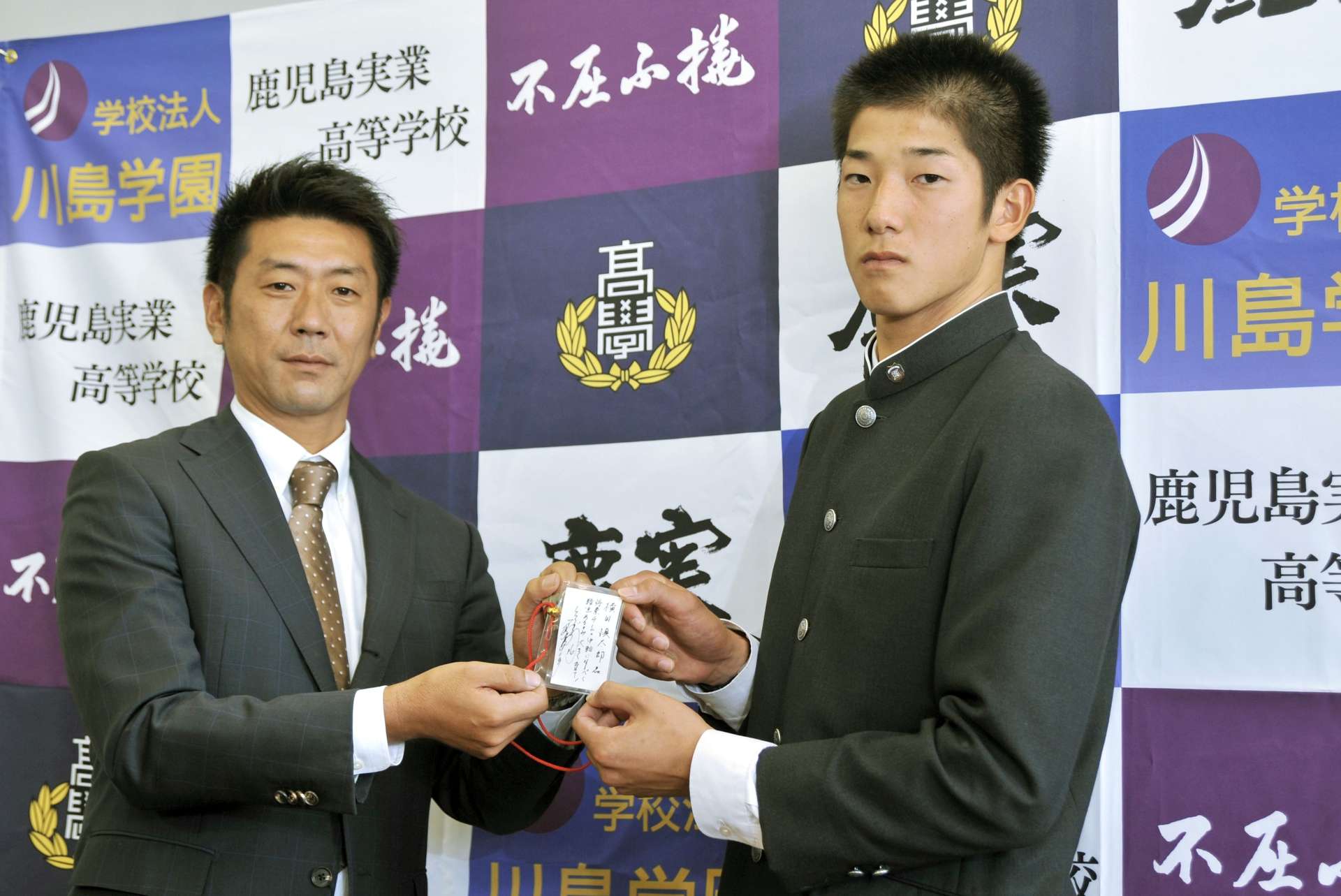 2013年10月、阪神の田中秀太九州担当スカウト（左）から和田豊監督直筆のメッセージを受け取る鹿児島実高の横田慎太郎選手＝鹿児島市の鹿児島実高