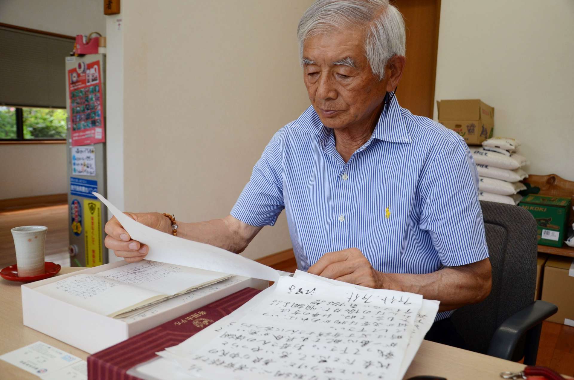 事件当時送られた支援者からの手紙を手に取る中山信一さん＝志布志市志布志