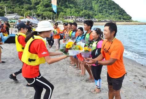 約３３０キロをこぎきり、支援者から歓迎されるメンバー＝２７日、鹿児島市の磯海岸