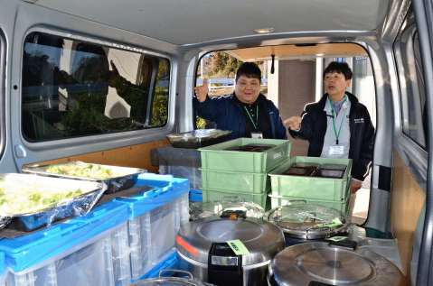 〈資料写真〉２０２１年２月、配送車に積んだ作業員の昼食をチェックする稲村光弘さん（右）＝福島県広野町