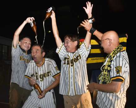 ビールをかけ合ってリーグ優勝の喜びを爆発させる阪神ファン＝１４日、鹿屋市向江町