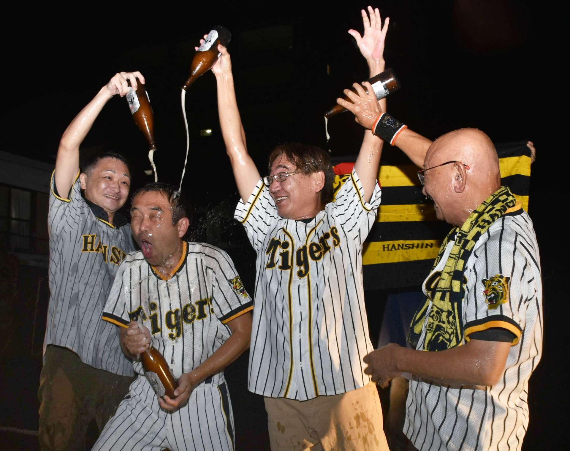 ビールをかけ合ってリーグ優勝の喜びを爆発させる阪神ファン＝１４日、鹿屋市向江町