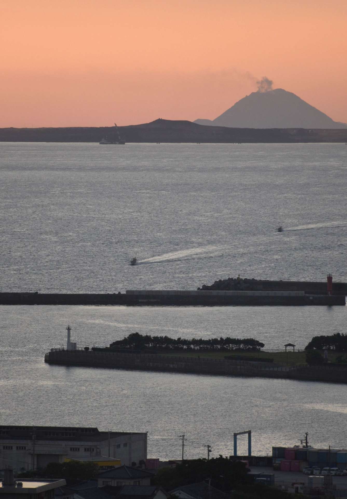 夕日でシルエットが浮かび上がった馬毛島の岳之腰。奥の島影は三島村・硫黄島＝１９日、西之表市