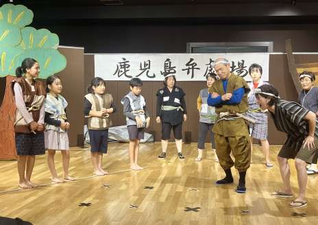 鹿児島弁の創作劇を発表する劇団「げたんは」のメンバーと児童＝１２日、鹿児島市のかごしま県民交流センター