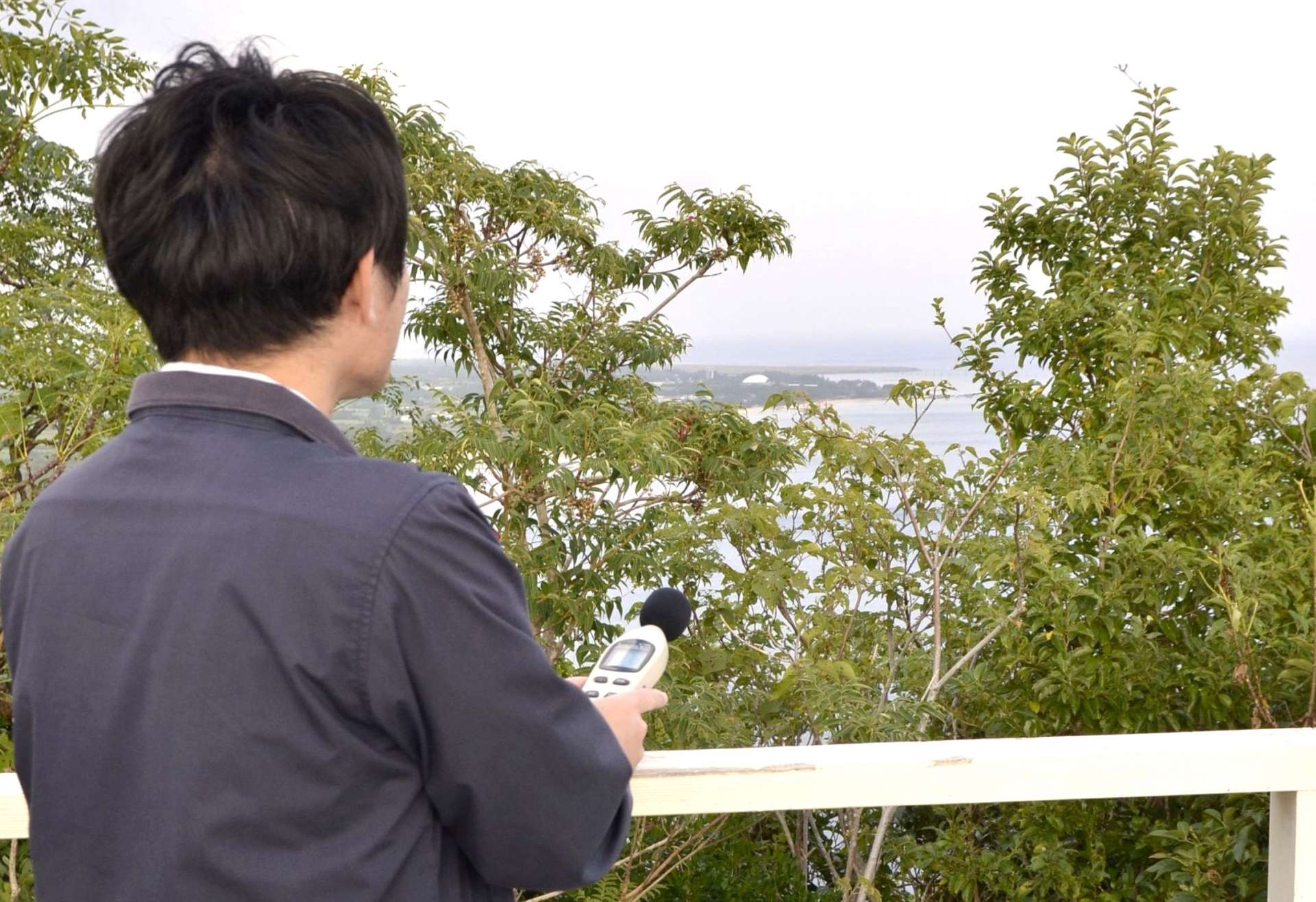奄美空港から約５キロ離れた高台で戦闘機の騒音を測定する西之表市職員＝１７日、奄美市の明神崎展望台