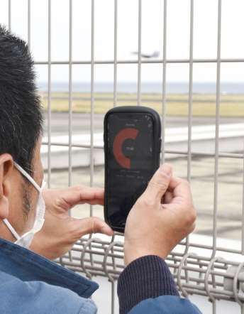スマートフォンアプリで戦闘機の騒音を測定する西之表市職員＝１７日、奄美市笠利の奄美空港