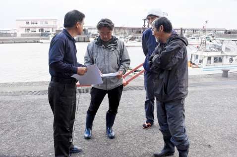 漁協職員から捜索区域の説明を受ける漁師＝３０日午前１０時半すぎ、屋久島町の安房港