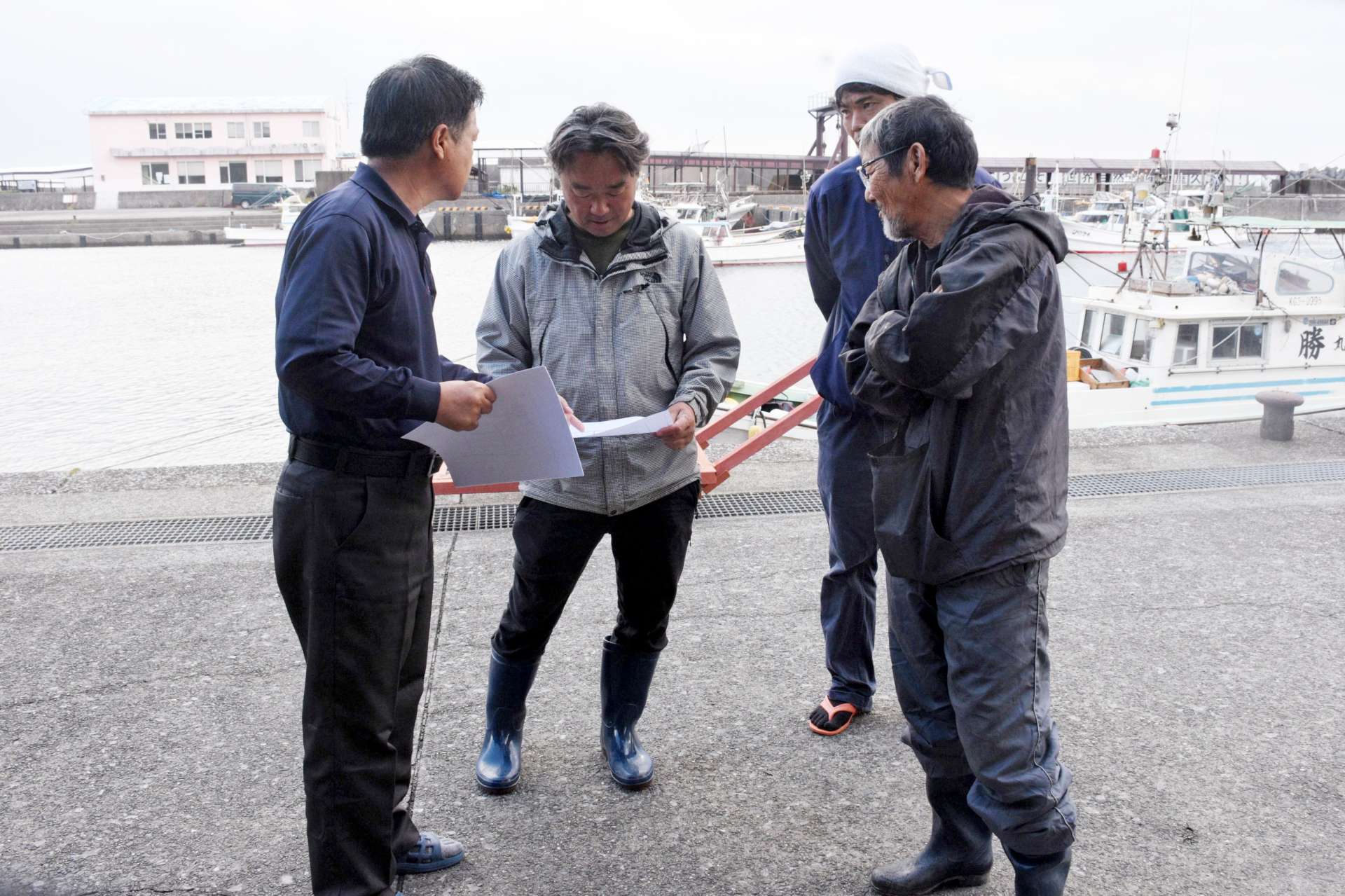 漁協職員から捜索区域の説明を受ける漁師＝３０日午前１０時半すぎ、屋久島町の安房港