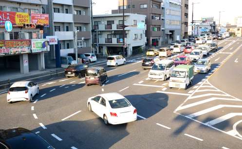 右折し外側の第１、２車線を走る車＝鹿児島市東郡元町の産業道路入口交差点