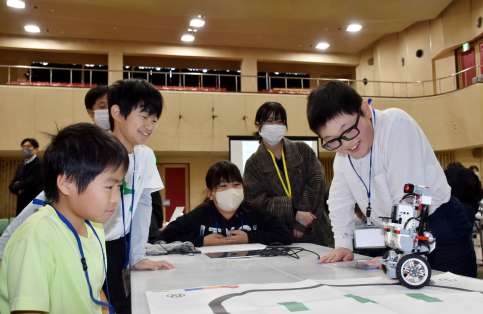 ロボットのプログラミングを楽しむ子供たちと鹿児島高専の鎌田鈴音さん（右から２人目）＝垂水市市民館