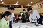 ロボットのプログラミングを楽しむ子供たちと鹿児島高専の鎌田鈴音さん（右から２人目）＝垂水市市民館