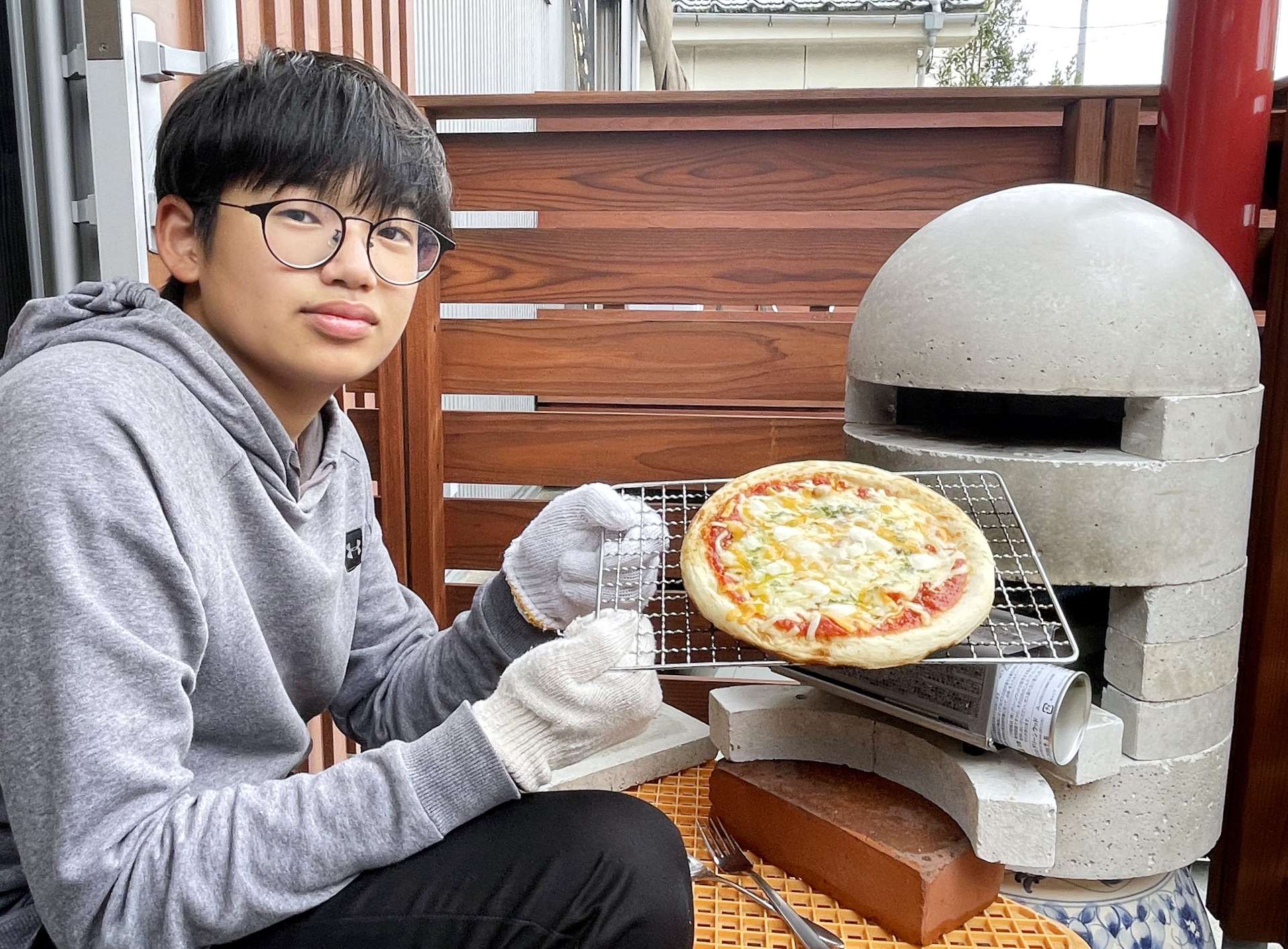 自作した窯でピザを焼き上げた石原田海秀さん＝鹿児島市城山１丁目
