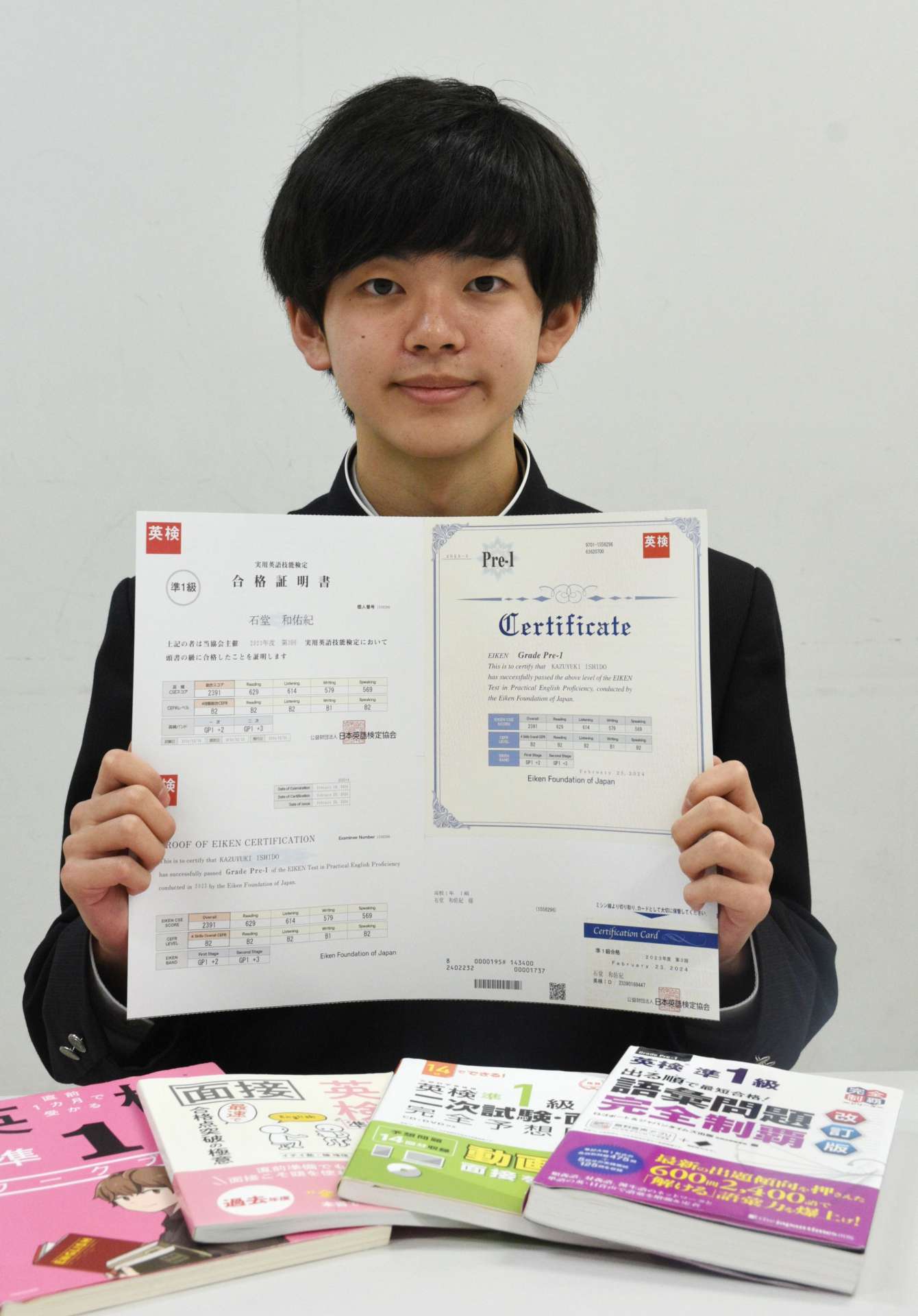 〈関連〉「単語や文法などの基礎知識習得に使った」という参考書を並べ、喜ぶ石堂和佑紀さん＝中種子町の種子島中央高校