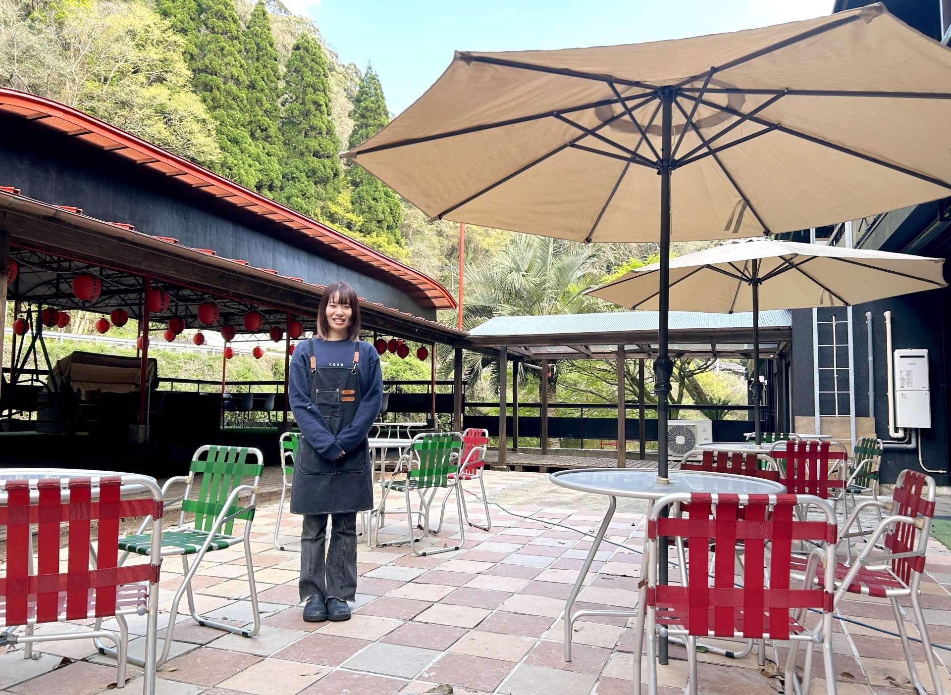 温泉カフェ「湯らり～な」テラス席に立つ浜弓場美来店長＝霧島市隼人町嘉例川
