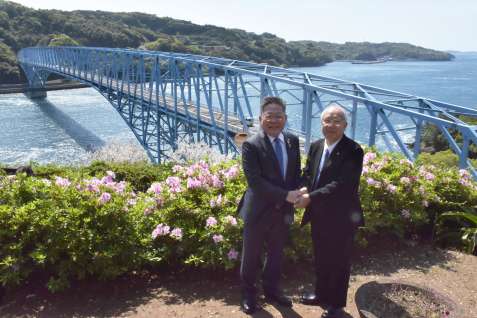 黒之瀬戸大橋を見下ろす展望所で、手を取り合う西平良将・阿久根市長（左）と川添健・長島町長＝９日、長島町山門野のうずしおパーク
