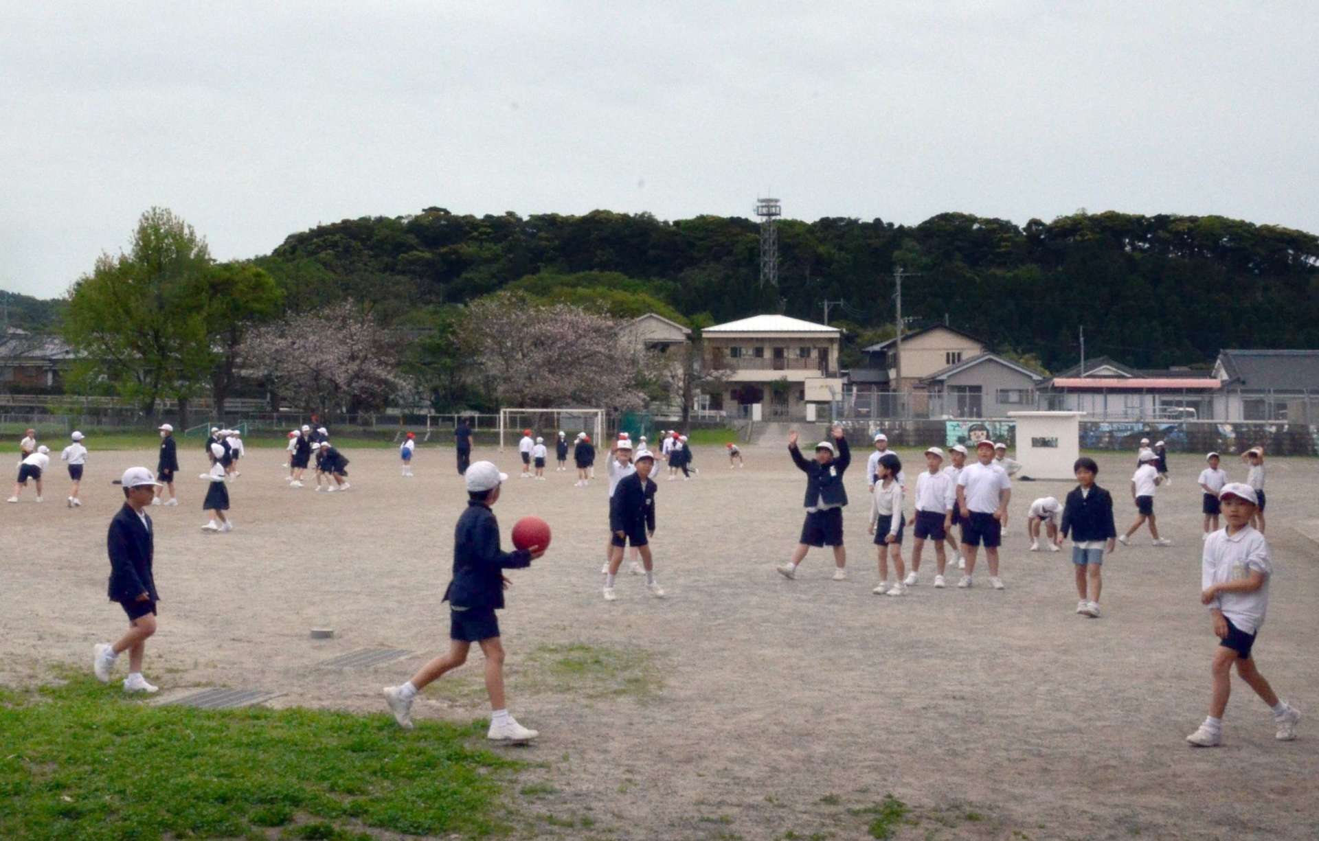 自然に囲まれた校庭で遊ぶ児童たち＝いちき串木野市の串木野小学校