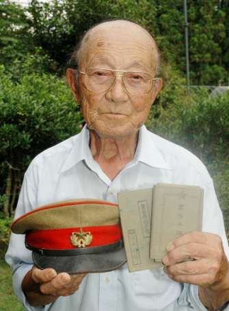 近衛兵の軍帽と軍隊手帳、青年学校手帳を手にする田上時男さん