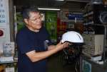 つば付きヘルメットを説明する冨ケ原多聞店長＝鹿児島市平之町のじてんしゃのトミハラ
