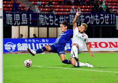 前半、シュートを放つ鹿児島Ｕの鈴木（左）＝鹿児島市の白波スタジアム