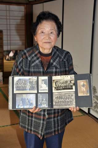荒田国民学校教員時代の写真を手にする長丸シズさん