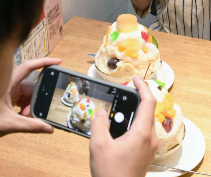 お目当ての白熊が届き、早速撮影する客＝鹿児島市千日町の「天文館むじゃき本店」