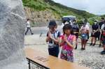 慰霊碑に手を合わせる沖縄の児童＝１４日、宇検村の船越海岸