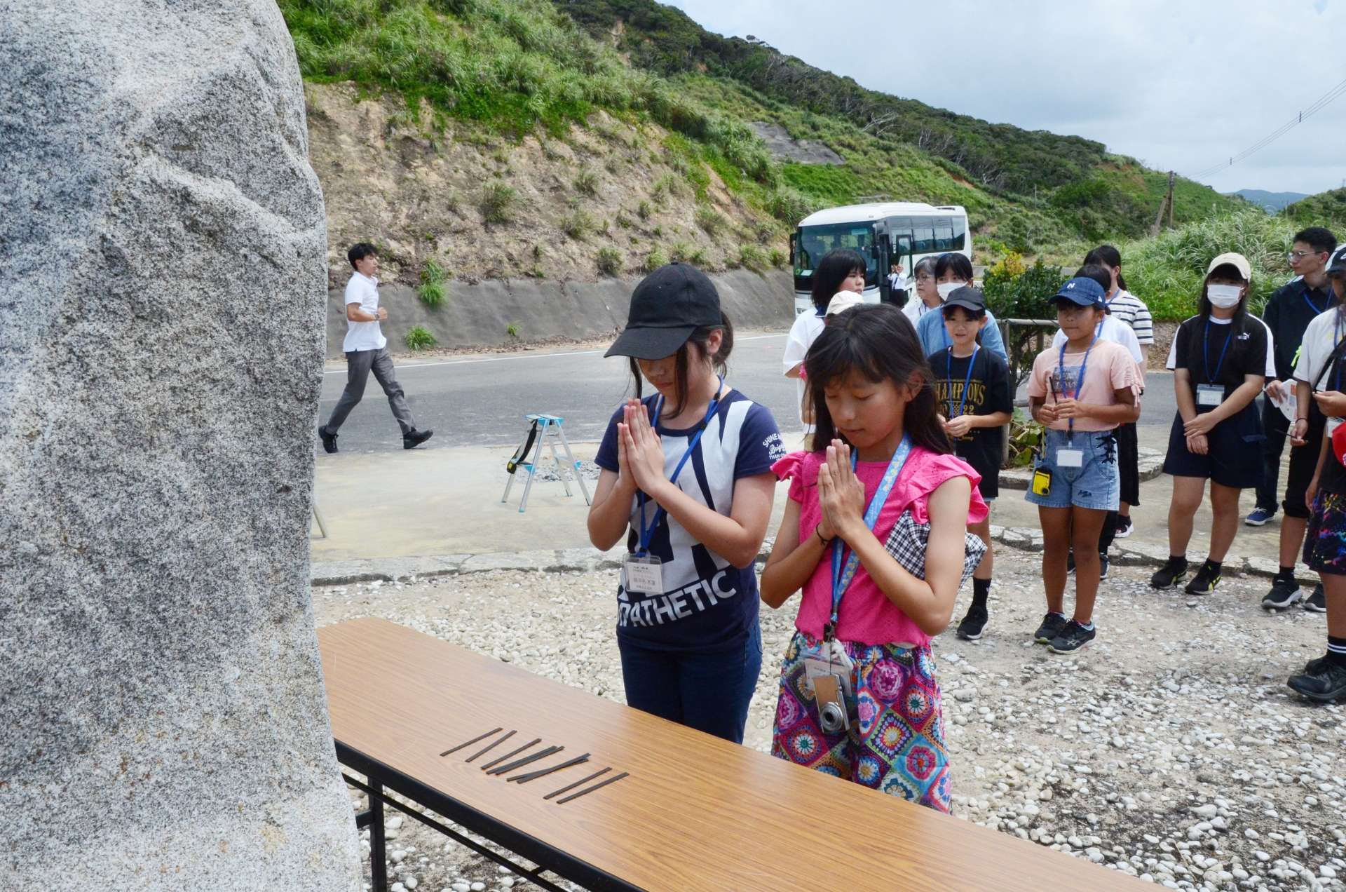 慰霊碑に手を合わせる沖縄の児童＝１４日、宇検村の船越海岸