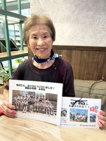 岡前小学校の児童から届いたメッセージ集を手にする有村恵子さん＝７月３０日、鹿児島市