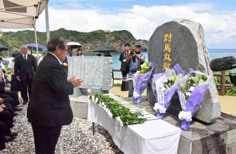 慰霊碑に花を手向け、手を合わせる津田政俊区長＝２４日、宇検村宇検の船越海岸